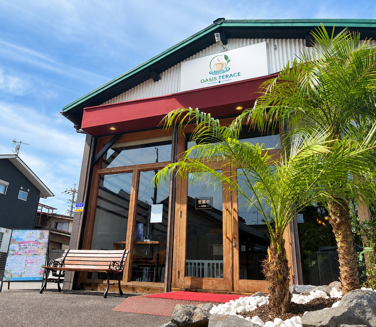 木の扉とヤシの木に迎えられる OASIS TERRACE の入口