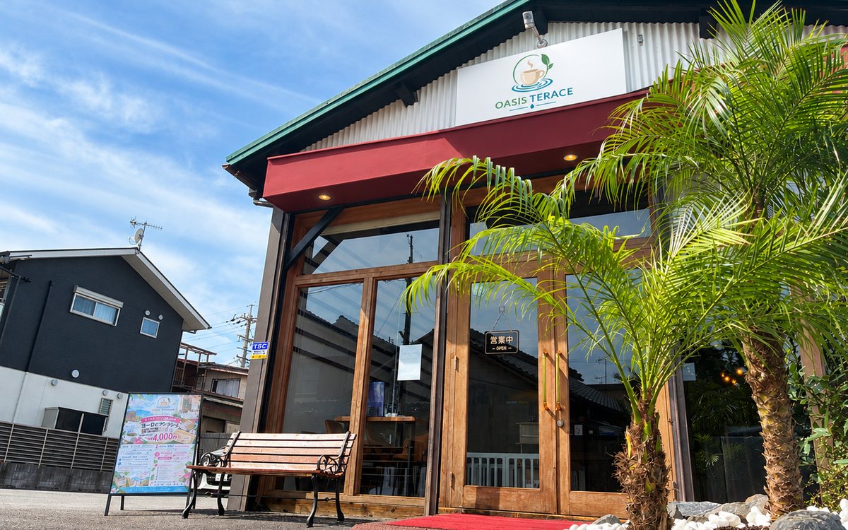 OASIS TERRACE の店舗外観。赤い壁とヤシの木が目印